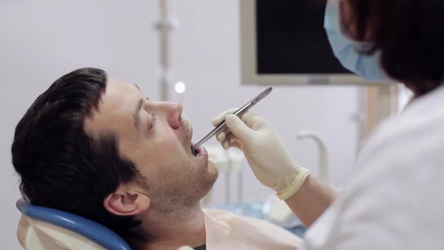 The dentist puts a cotton ball near the patient's tooth.