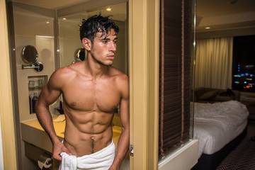 Handsome shirtless muscle young man going out of shower in hotel room. Horizontal indoors shot