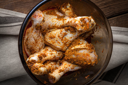 Marinated chicken drumsticks in a glass bowl.