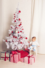 Cheerful little baby boy playing near the Christmas tree