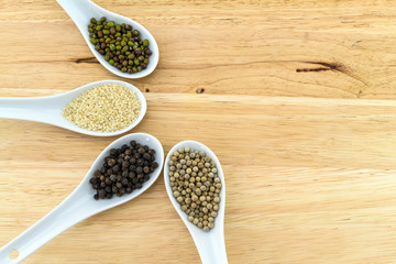 Green bean , white sesame ,black and white pepper in white ceramic spoon