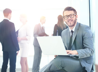 Portrait of a handsome young business man with people in background at office meeting