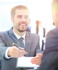 Fototapeta premium Businessman giving a pen to seal deal with his partner