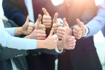 Close-up of business team holding their thumbs up