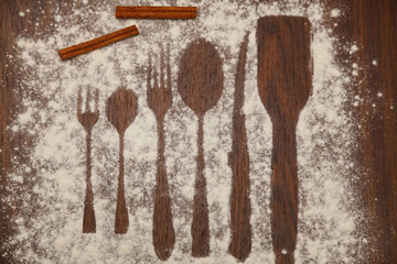 Spoons and forks and knife, flour sprinkled the wooden plank.