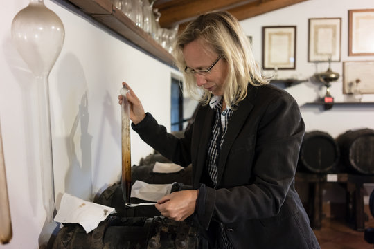 Woman serving herself test sample of balsamic condiment for tasting