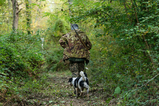 Truffle hunter and his dog walking through forest