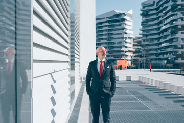 Middle-age contemporary businessman posing outdoor in the city, hand in pocket, overlooking - pensive, serious, thoughtful concept