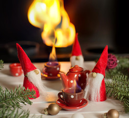 Santa's helpers sitting near fireplace with xmas decorations and drinking hot tea. Christmas fairy...