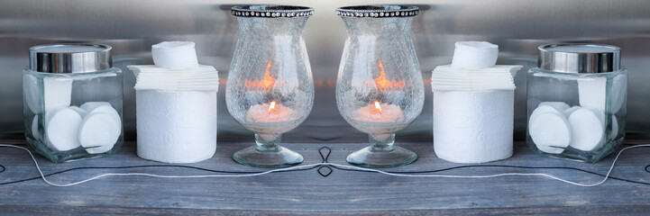 Paper napkins, toilet paper, cotton pads, burning candle on wooden table. Wide panoramic image,