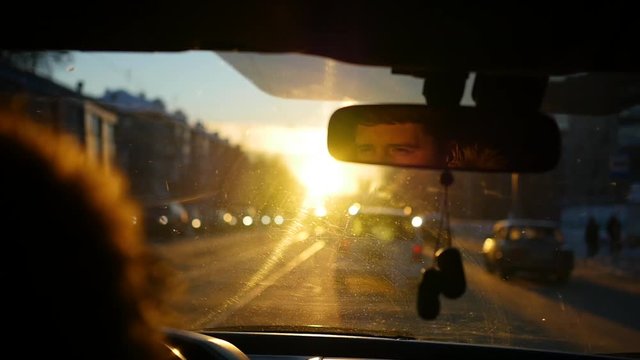 The man driving the car under sunset sky reflection in the rear view mirror