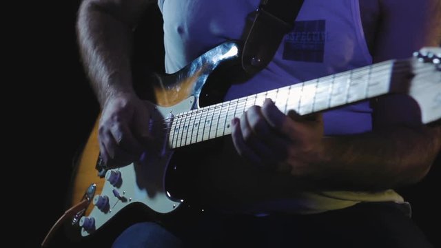 Musician plays heavy rock by electric guitar at the dark record studio