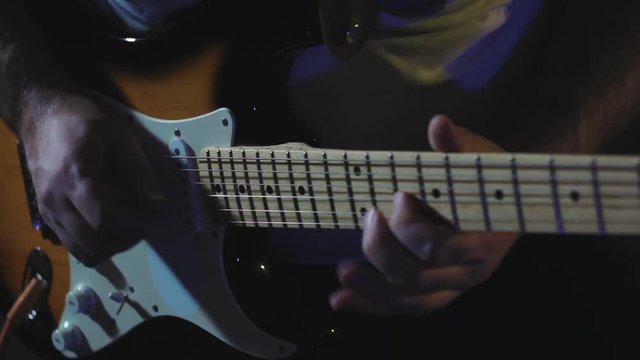 Guitarist plays hard rock by electric guitar at the dark record studio close-up