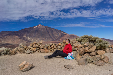 Obraz premium Young female hiker is resting with beautiful view of Mount Teide volcano. Tenerife, Canary Islands, Spain.