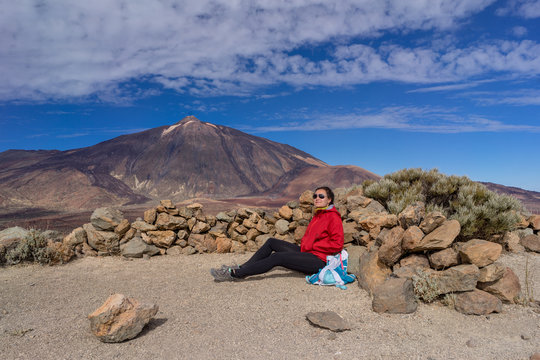 Young female hiker is resting with beautiful view of Mount Teide volcano. Tenerife, Canary Islands, Spain.