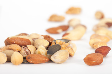 Obraz premium Heap of mixed nuts: Pistachios, peanuts, walnuts, almonds, hazelnuts, Brazil nuts and cashews on white background