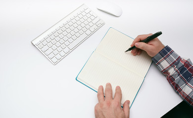 Writing.Human hand with pen calculating budget.Computer keyboard and mouse on a table.