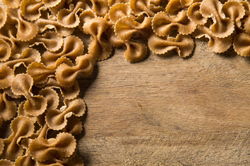 Top view of uncooked pasta integral on a wooden background