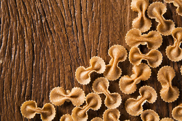 Top view of uncooked pasta integral on a wooden background