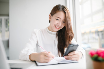 indoor picture of smiling Asia woman with notebook and pen