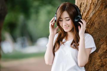 young beautiful Asia woman listening music headphones outdoor