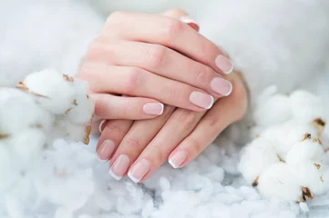 Draagtas Woman hands with beautiful French manicure holding delicate white cotton flower © Zoja