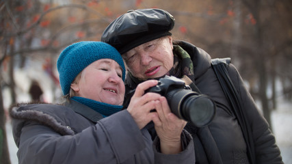 Obraz premium Two senior woman looking to they self photo camera at winter day, outdoor