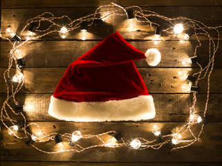 Santa Claus hat  on wood background surround by light bulbs
