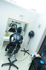 Woman in hairdresser, drying hair under machine