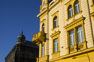 Fototapeta premium Beautiful renovated old historical townhouse in the city. Architecture has bright yellow facade. Ugly desolated house in the background. 