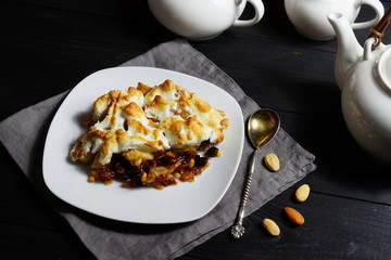 apple pie with nuts on a white plate and a dark background 