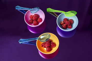 fashion background with raspberries on multicolored containers