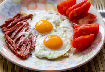 Breakfast, scrambled eggs, bacon and tomatoes.
