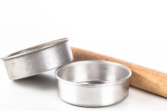 Round Metal Cooking And Baking Pans With A Wooden Rolling Pan On A White Background