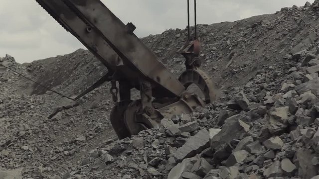 Excavator charging shovel with stones and transporting to truck