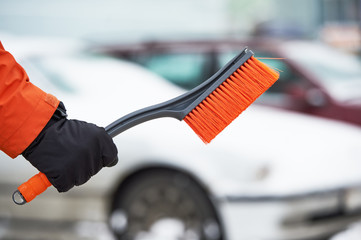 Snowy car cleaning concept. Hand with brush in winter