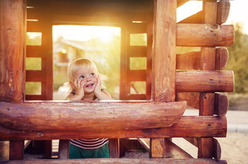 baby girl in wooden house on the playground at sunset
