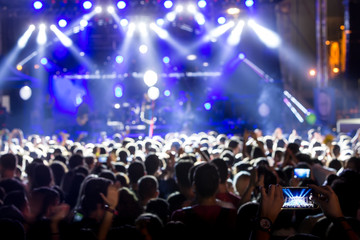 Fototapeta na wymiar Hand with a smartphone records live music festiva