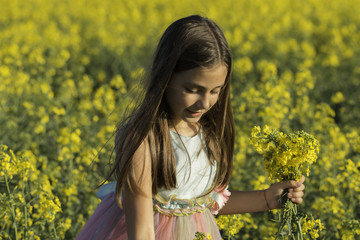 Naklejka na ściany i meble Happy Beauty young girl playing in yellow rape field in rural countryside. Portrait shot, Happy Freedom outdoors concept.