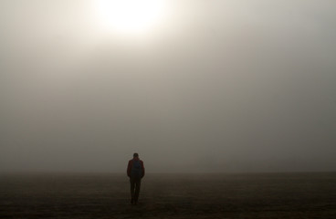  hiker walks alone in a sea of sand in the fog