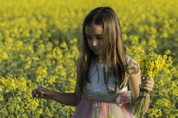 Happy Beauty young girl playing in yellow rape field in rural countryside. Portrait shot, Happy...