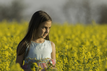 Naklejka na ściany i meble Happy Beauty young girl playing in yellow rape field in rural countryside. Portrait shot, Happy Freedom outdoors concept.