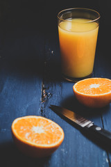 Fresh juice and citrus fruits on dark blue wooden background