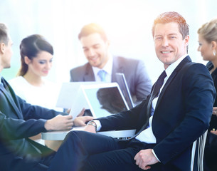 Portrait of mature business man smiling during meeting with colleagues in background