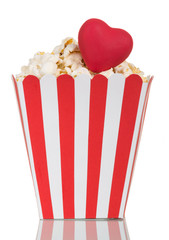 Popcorn in a striped paper box and red heart isolated on white