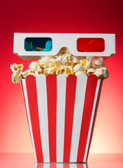 The square striped box with popcorn and 3D glasses on a red