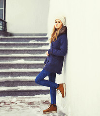 Fashion pretty cool girl wearing jacket and hat in winter city