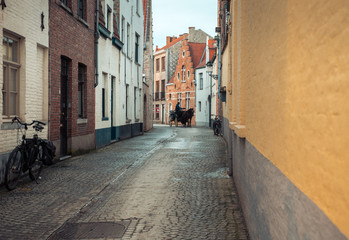 Horseman on the narrow street in Bruges, Belgium