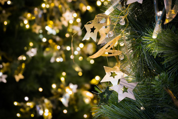 Star hanging on christmas tree with bokeh light in green yellow golden color, holiday abstract background, blur defocused