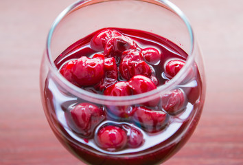 Cherry jam close up of a wine glass on a background of wood
